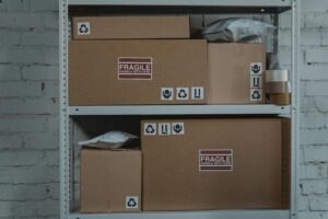 Cardboard boxes labeled 'Fragile' stacked on metal shelving in a storage room.