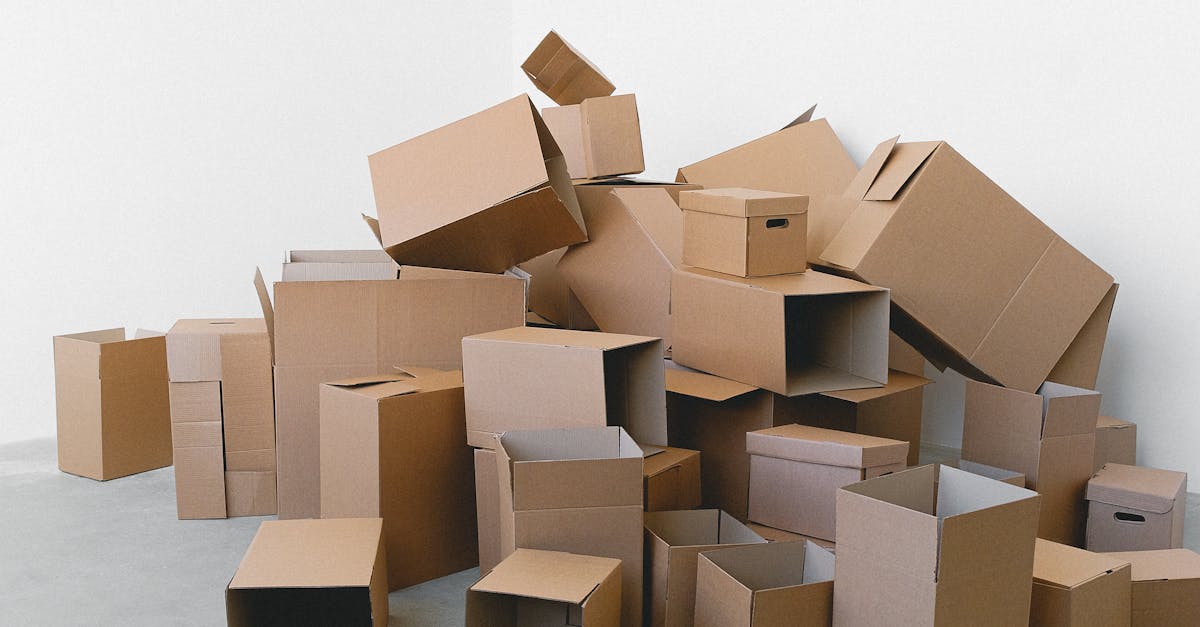 A stack of various sized cardboard boxes in an empty room with a white background.
