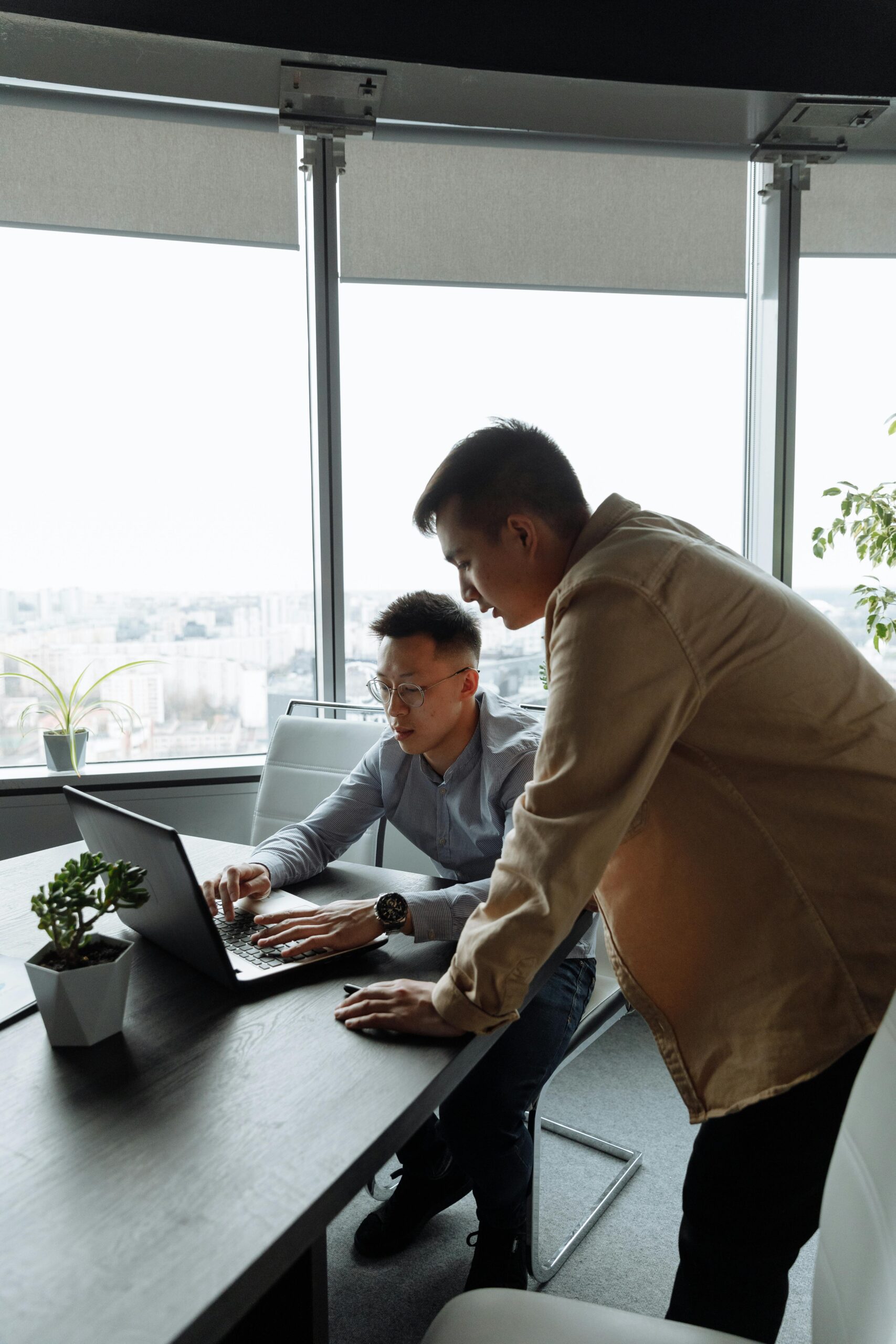 Two men collaborating at a laptop in a modern office space. Ideal teamwork concept.